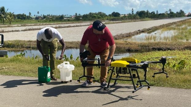 Two men preparing drones for electrostatic spraying.