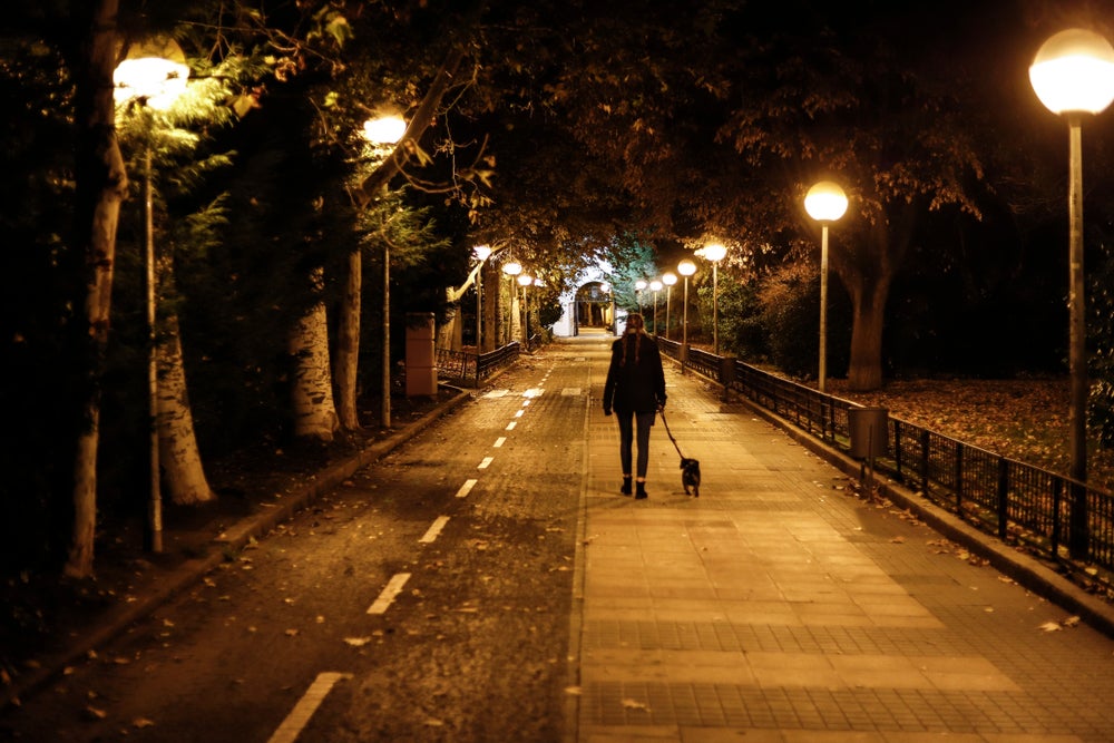 mujer paseando el perro en la noche con un carril bici
