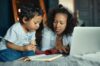 madre y su hijo de 3 años ven juntos un libro y una computadora