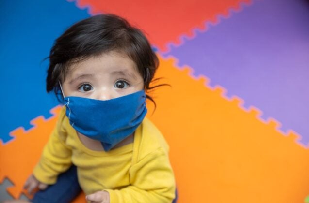 Niño de un año usando una mascarilla en jardín de infantes