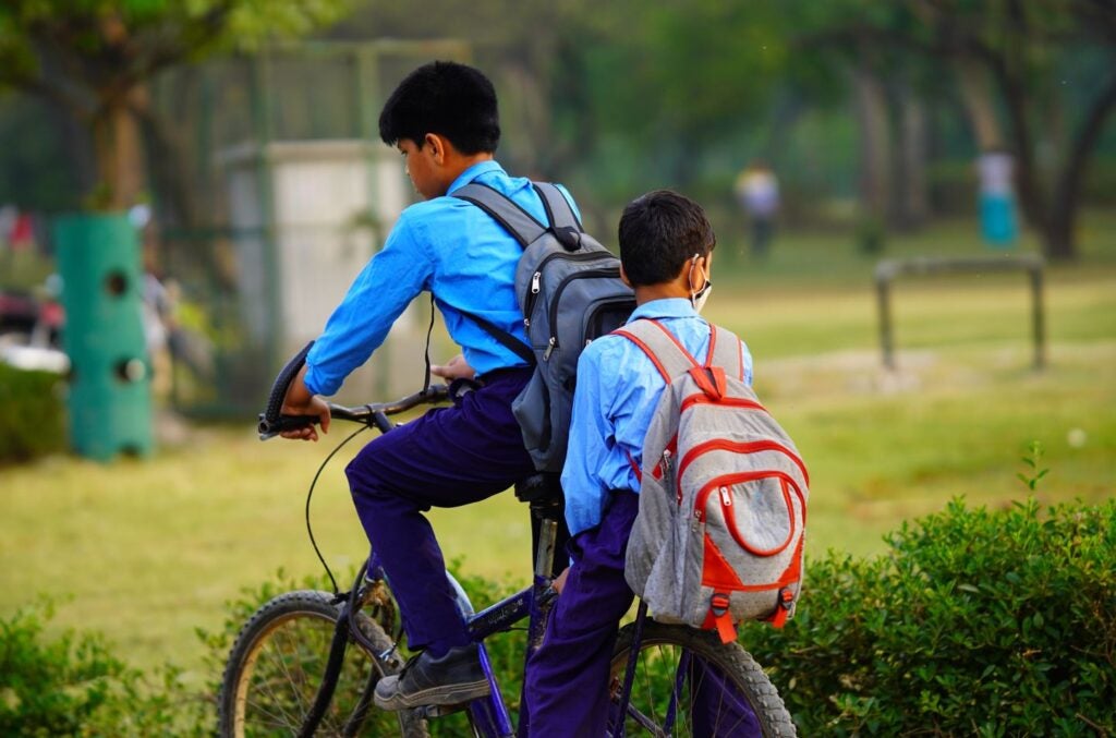 Dos niños en bicicleta se dirigen a la escuela luego de la pandemia