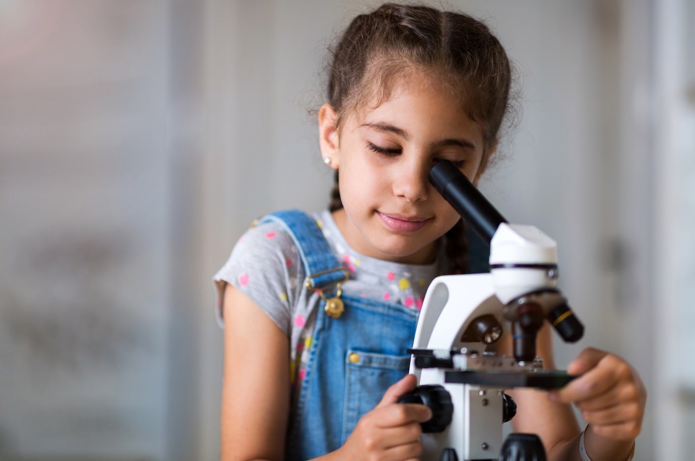 niña mira a través de un microscopio