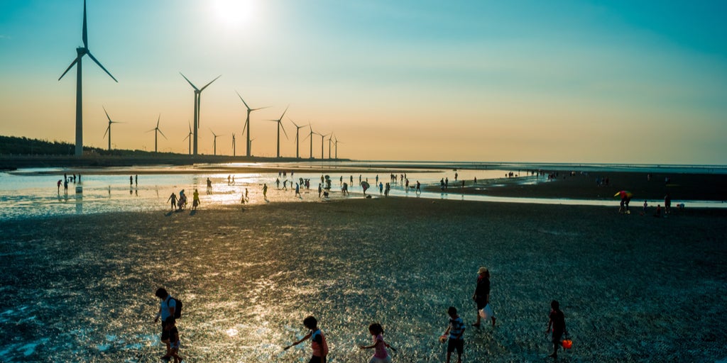 Turbinas eólicas en el mar sobre puesta del sol- personas caminando