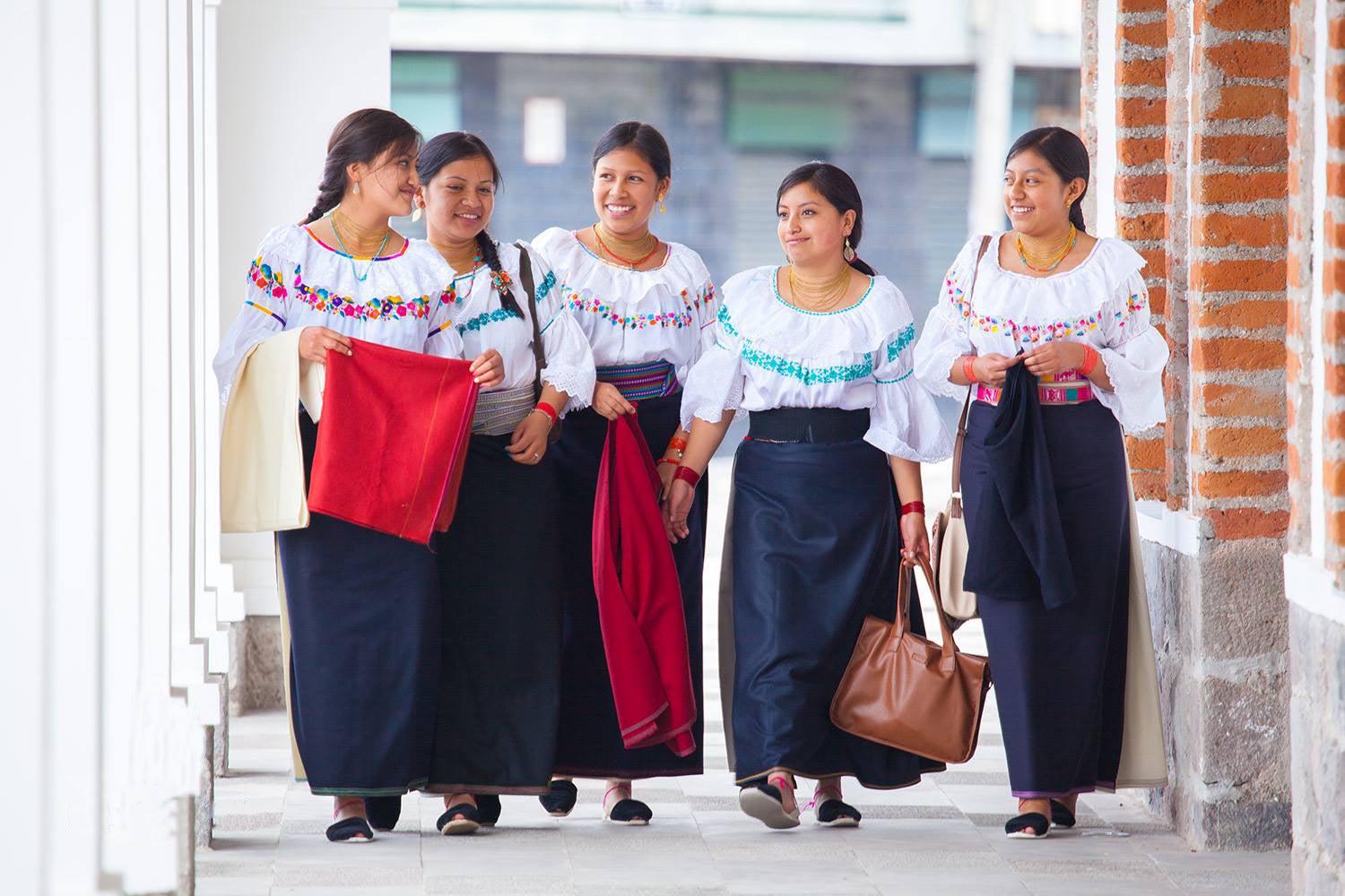 Cuatro mujeres indígenas caminando por un pasillo.