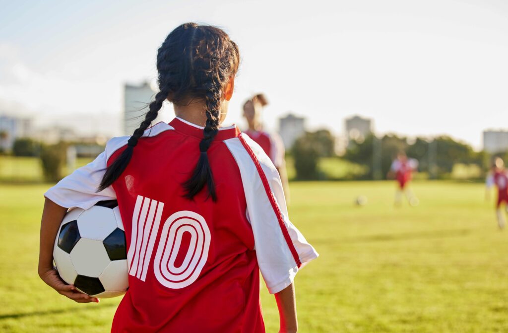 Little girl with a soccer ball under her arm. Women's soccer team.