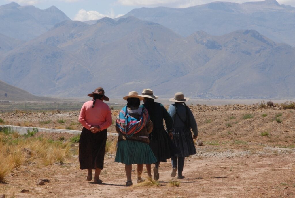 Mujeres bolivianas caminan en un entorno rural usando vestimentas tradicionales