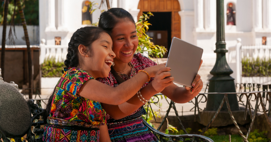 Dos niñas indígenas mayas sonríen y utilizan una tablet