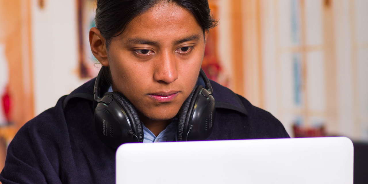 Joven indígena latinoamericano trabajando en una laptop.