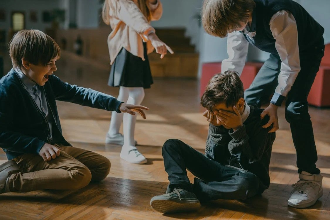 Niños burlándose de otro en salón de clase.