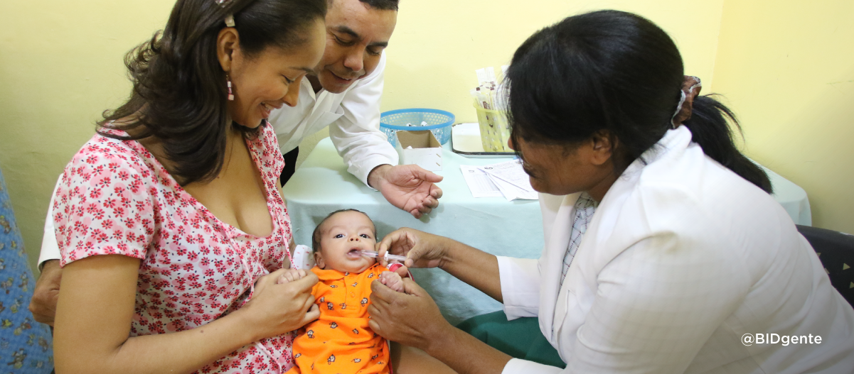 Una profesional de la salud examina a una bebe junto a sus padres