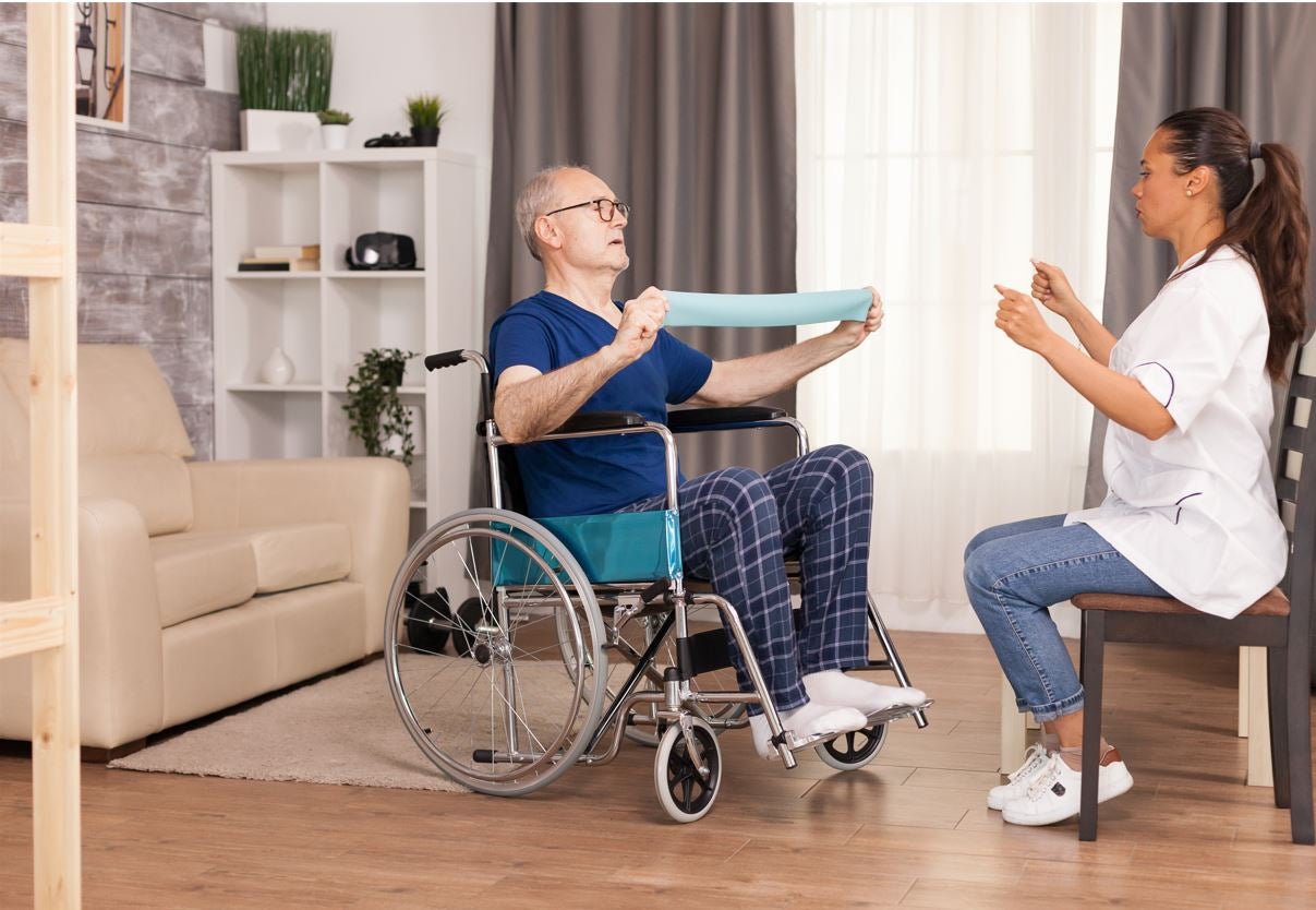 Una persona mayor hace ejercicio con una cuidadora