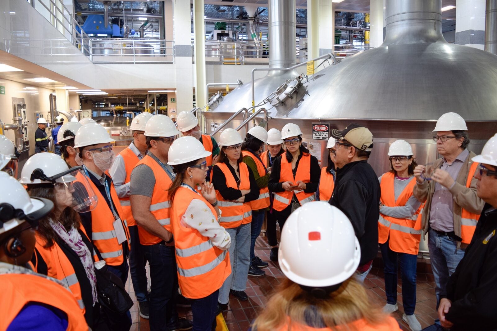 People in orange vests and white hard hats visiting a facility