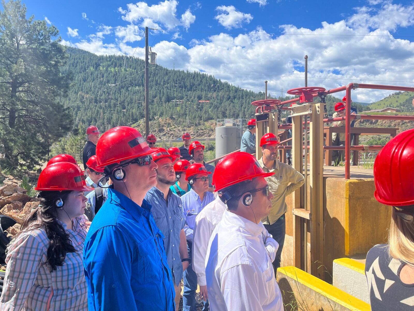 people in red hard hats visiting a facility
